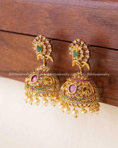 Gold-plated jhumka earrings with CZ, ruby, and emerald accents and pearl drops.