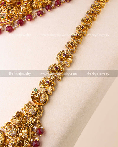 Detailed view of Nakshi temple necklace with intricate goddess motifs, ruby drops, and CZ embellishments.