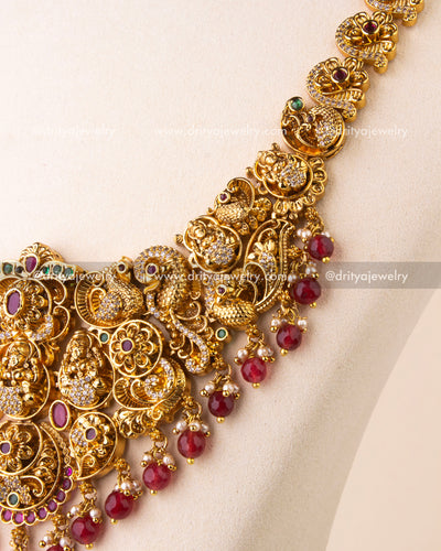 Detailed view of Nakshi temple necklace with intricate goddess motifs, ruby drops, and CZ embellishments.