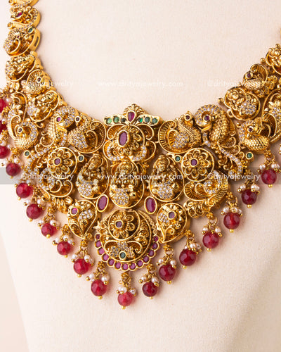 Detailed view of Nakshi temple necklace with intricate goddess motifs, ruby drops, and CZ embellishments.