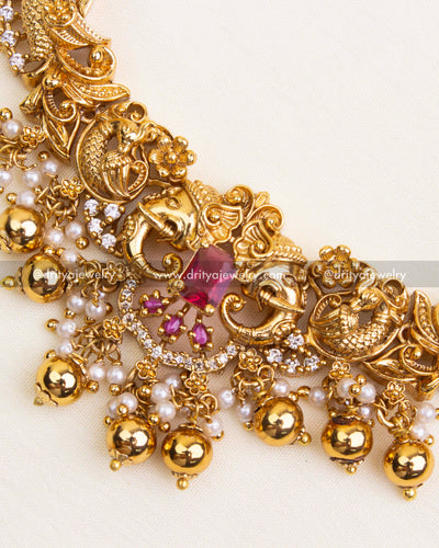 Detailed view of Nakshi engravings with ruby stones, gold beads, and American Diamonds on necklace.