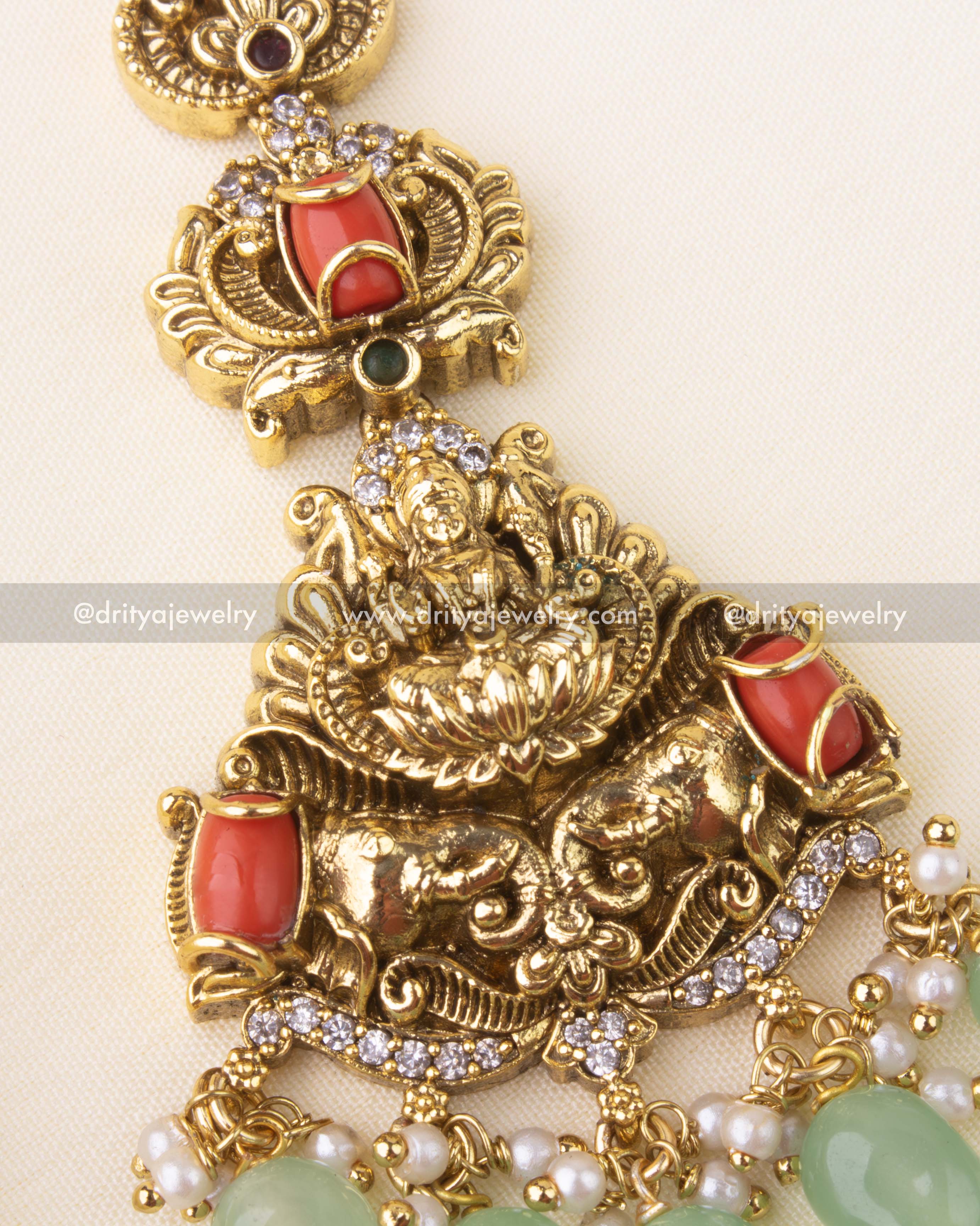 Detailed view of temple-style maang tikka with Lakshmi Devi, coral stones, and green bead drops.