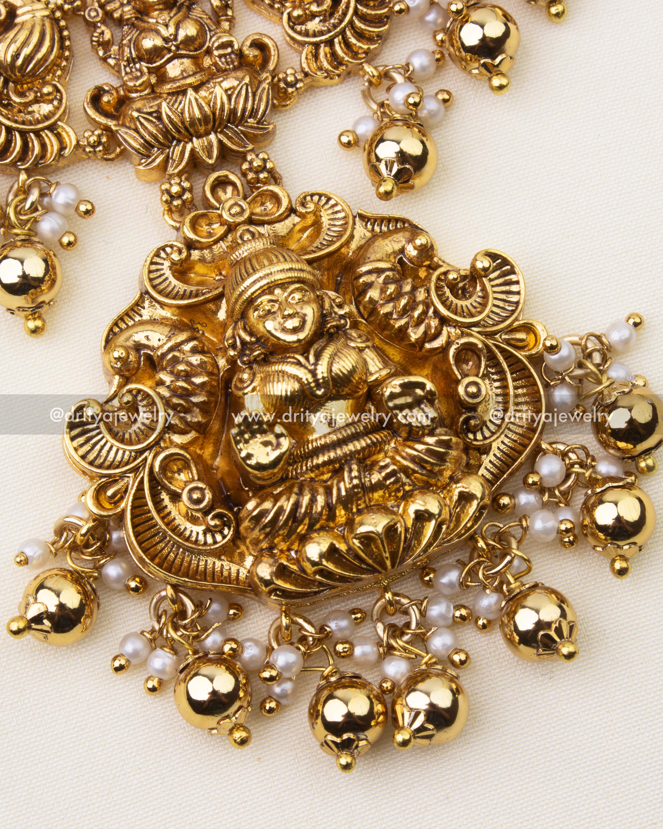 Detailed view of intricate nakshi carvings with ruby and green stone accents on Kanti short necklace.