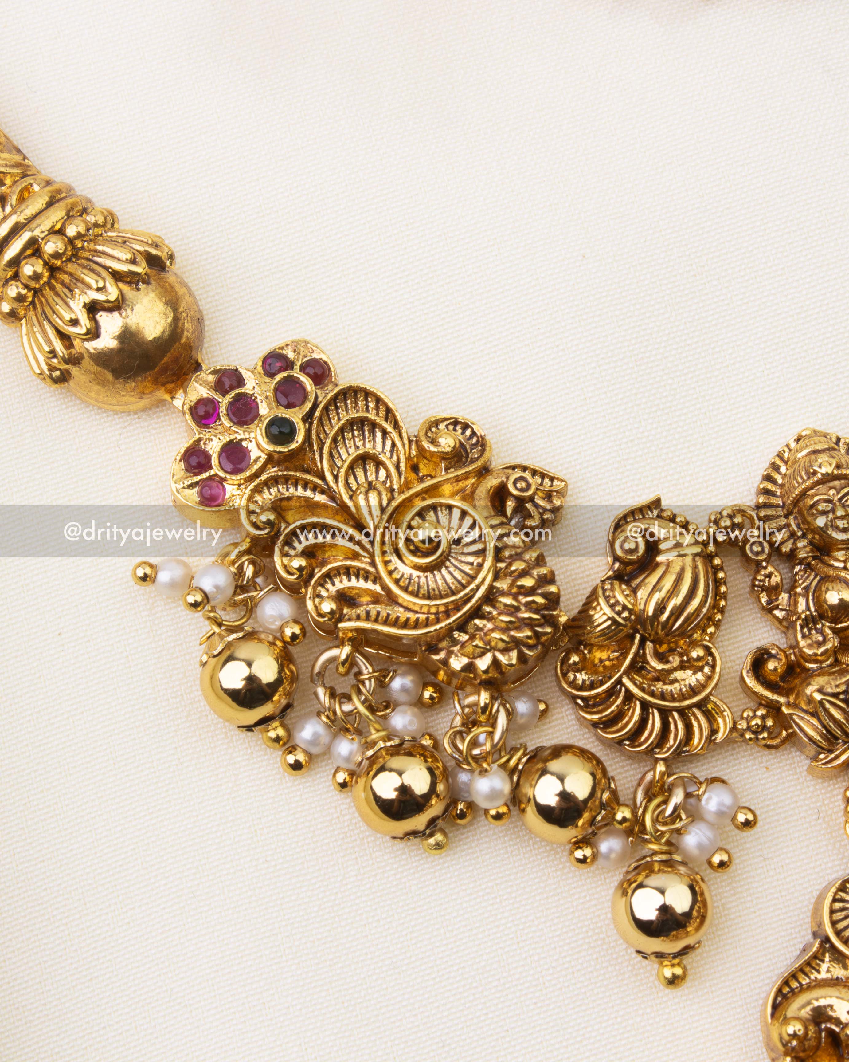 Detailed view of intricate nakshi carvings with ruby and green stone accents on Kanti short necklace.