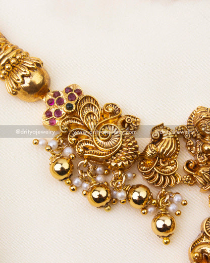 Detailed view of intricate nakshi carvings with ruby and green stone accents on Kanti short necklace.