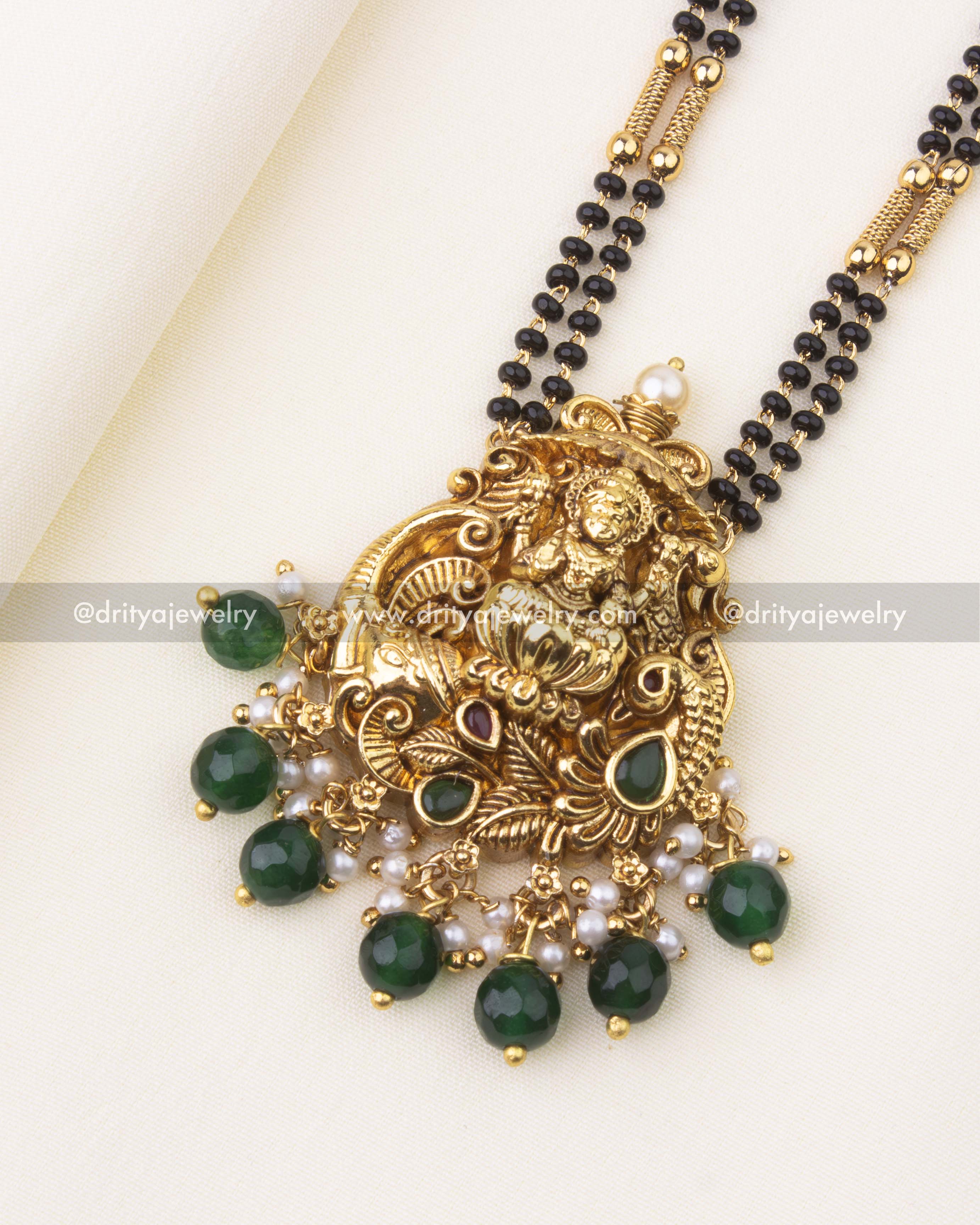 Detailed close-up of Goddess Lakshmi Nakshi pendant with Kemp stones, pearls, and green bead danglers.