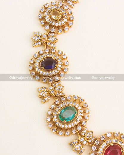 Detailed close-up of multicolor navaratna stones surrounded by CZ halo design in a short gold necklace.