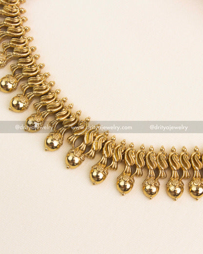 Handcrafted golden droplet edging on antique finish necklace for a traditional South Indian look.