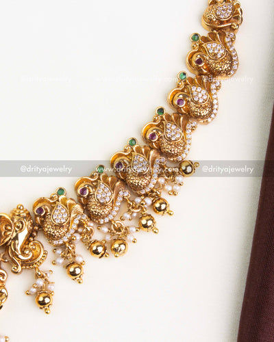 Lakshmi pendant with peacocks, floral detailing, and pearl-gold bead hangings in nakshi jewelry.