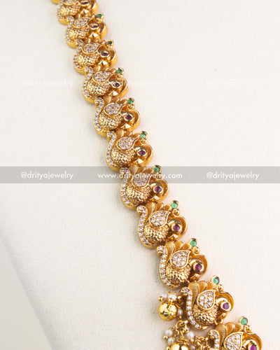 Detailed peacock motif chain with ruby and emerald highlights in temple jewelry long necklace.