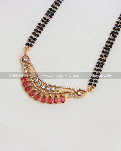 Close-up of intricate red stone and cubic zirconia pendant on black beads necklace.