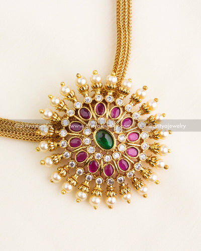 Intricate circular pendant with ruby, emerald, and CZ stonework in sunburst design.