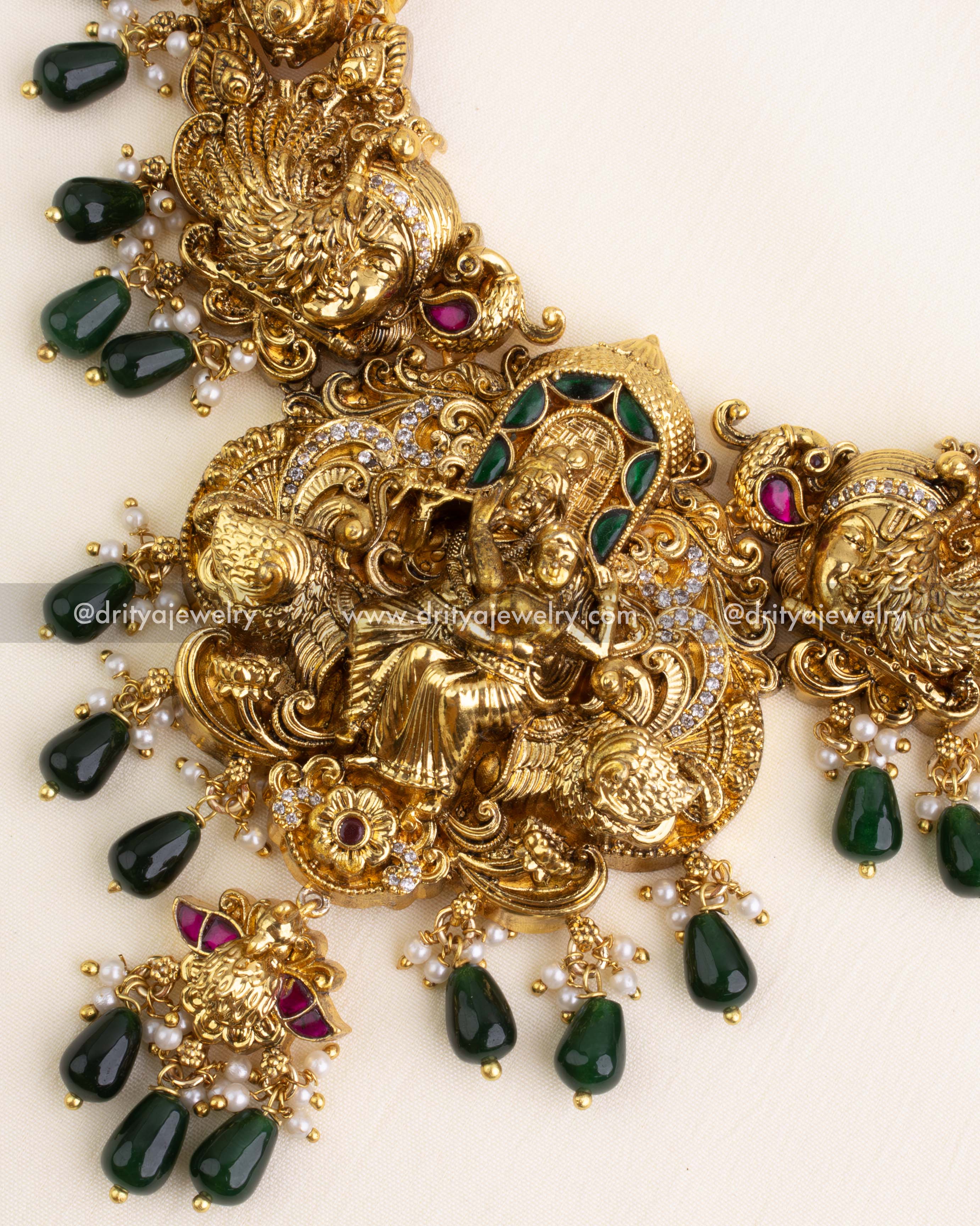 Detailed Krishna-Parvati pendant design with ruby highlights, emerald enamel, and teardrop bead clusters.