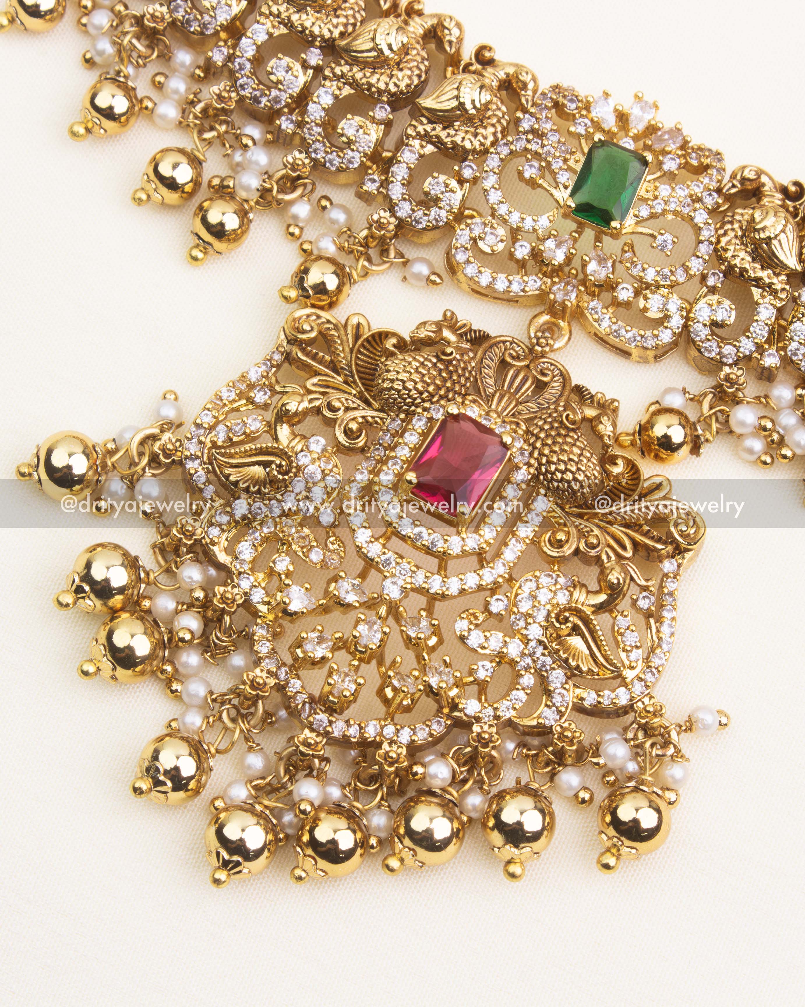 Detailed antique short necklace pendant with red CZ stone, floral Nakshi work, and pearl-gold danglers.