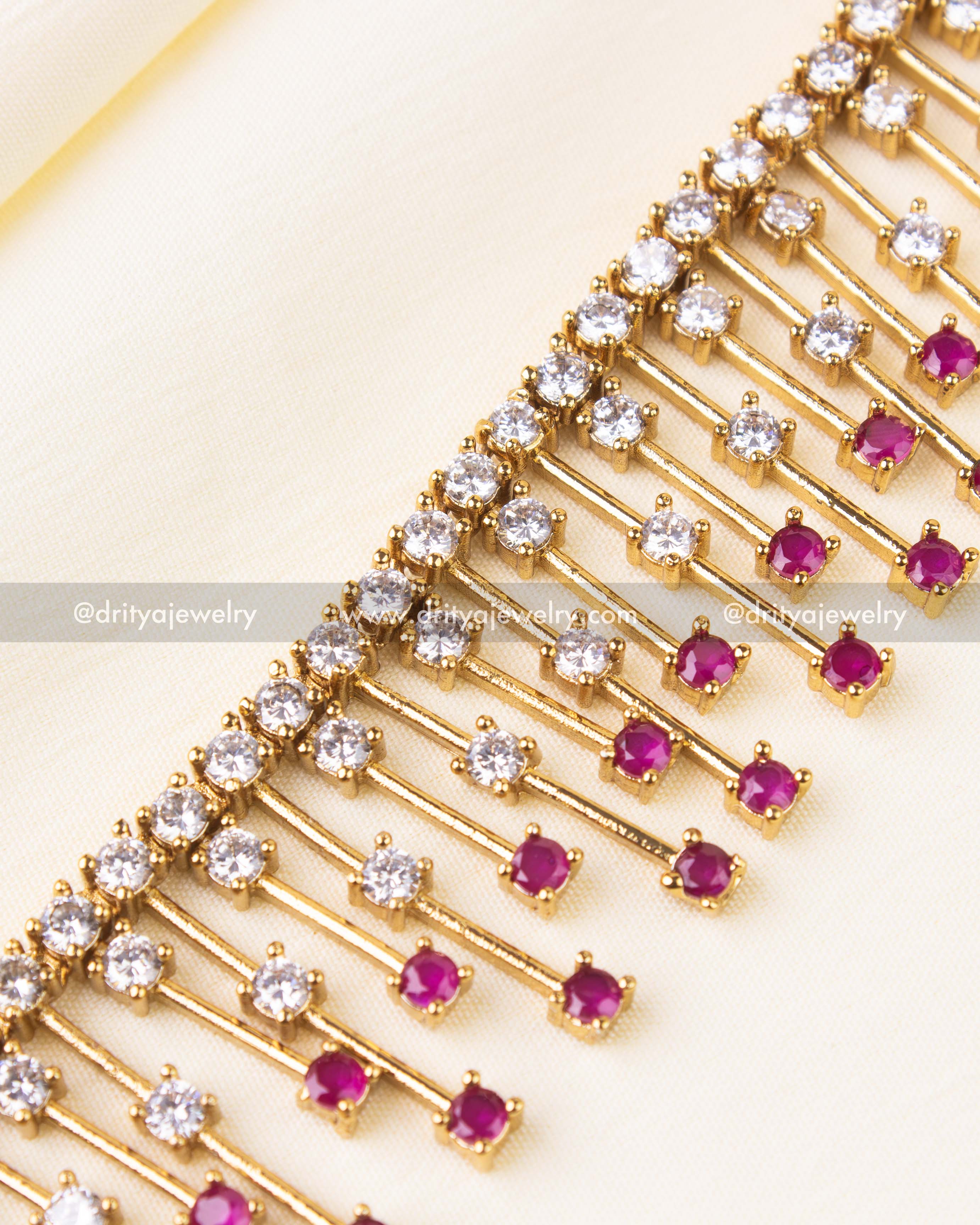 Detailed view of necklace with alternating pink and white CZ stones on golden drop lines.