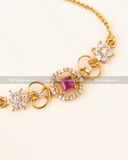 Pink square stone encircled by CZ stones with floral accents and gold finish.