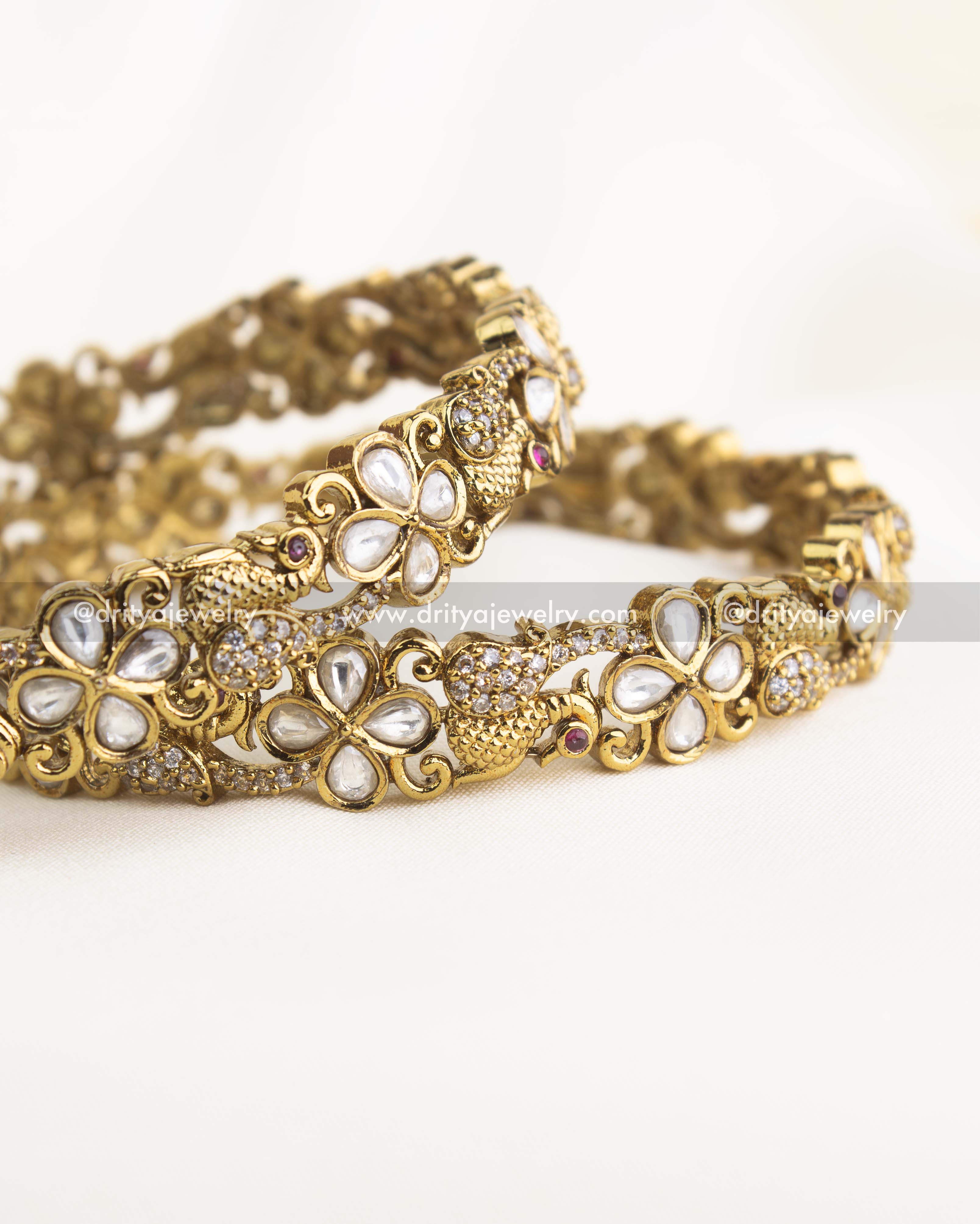 Handcrafted antique gold bangles featuring uncut Polki and Kundan floral designs with ruby accents.