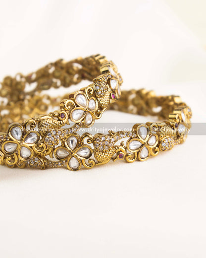 Handcrafted antique gold bangles featuring uncut Polki and Kundan floral designs with ruby accents.