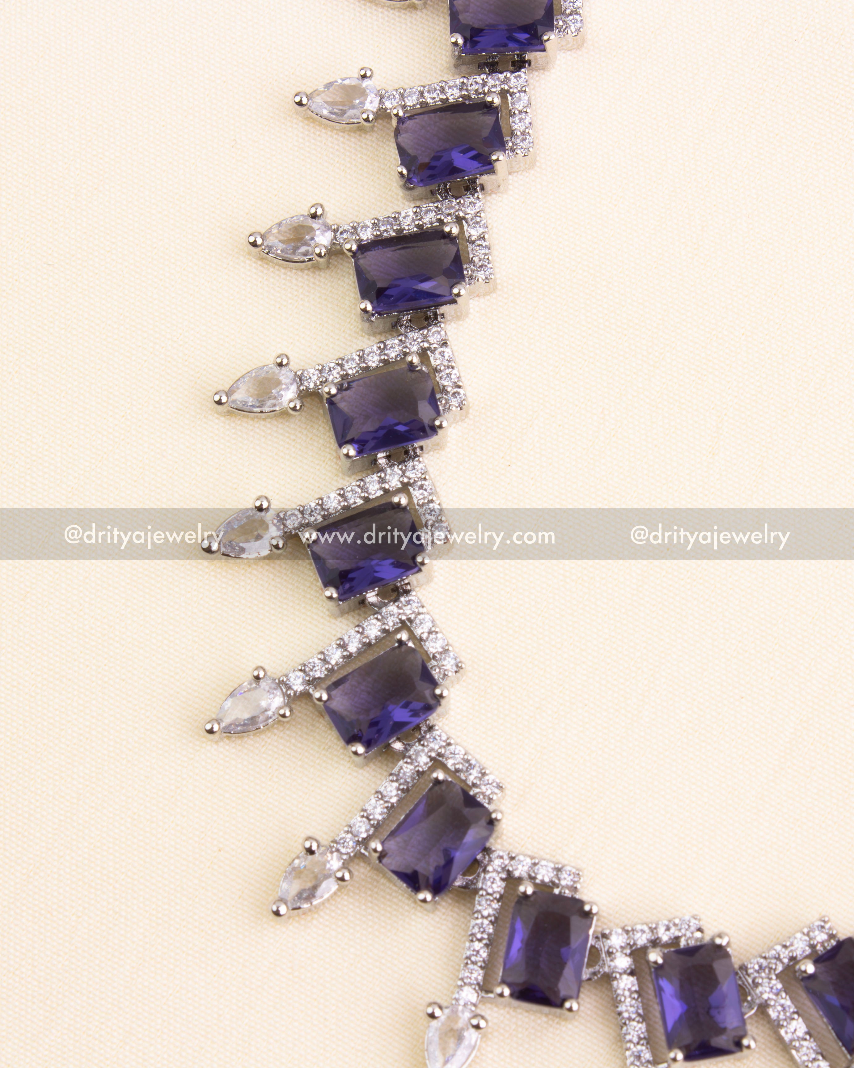 Emerald-cut purple stones framed by CZ in a pointed design