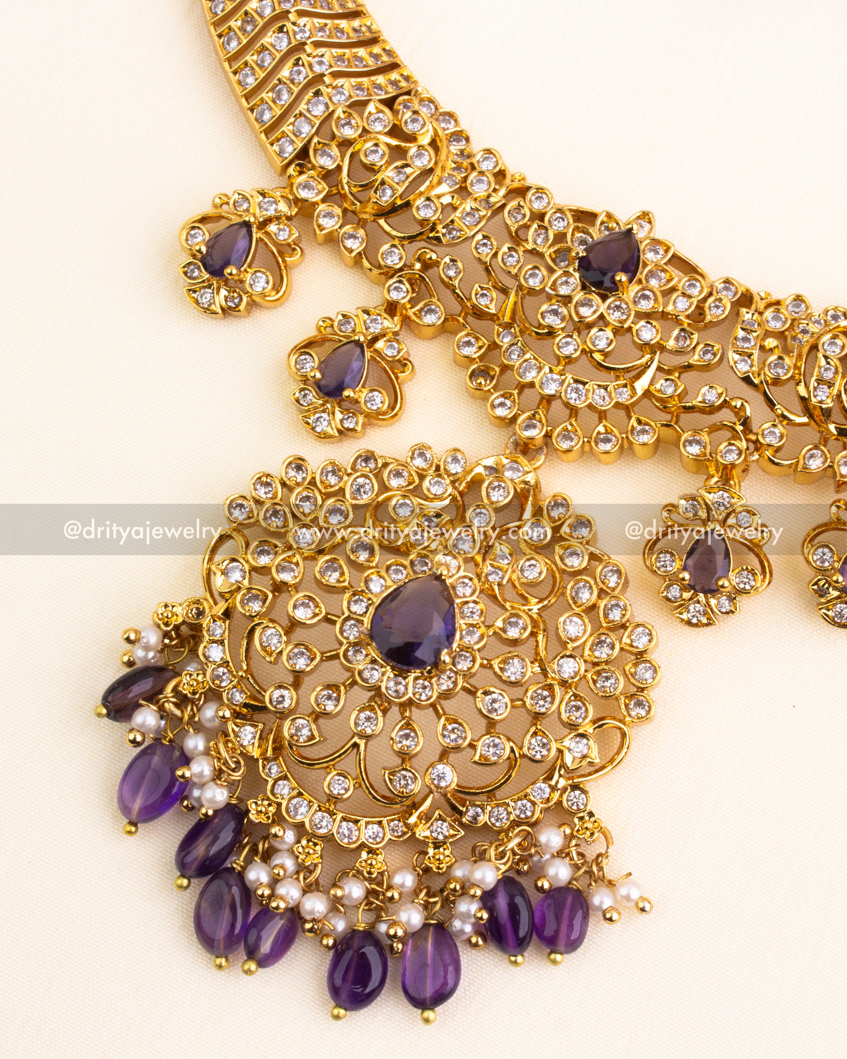 Detailed pendant design with purple teardrop center and pearl-purple bead danglers.