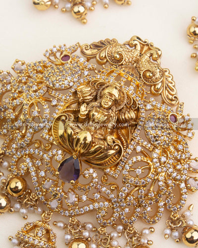 Ornate Lakshmi pendant featuring CZ embellishments, purple gemstone, and traditional pearl clusters.