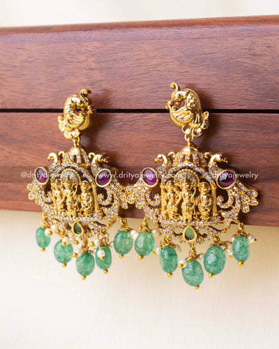Zoomed-in view of Ram Parivar earrings showcasing intricate deity carvings and green stone drops.