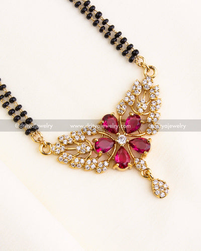 Detailed image of red stone flower pendant with surrounding CZ and gold detailing.