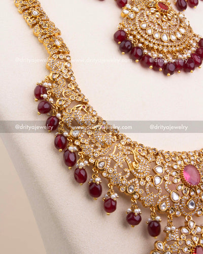 Detailed view of chain with floral and peacock motifs in red kundan and gold finish.