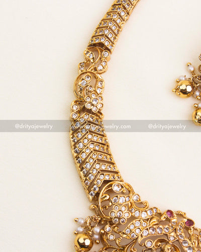 Detailed pendant view with Lakshmi idol, CZ stones, and red teardrop accents.