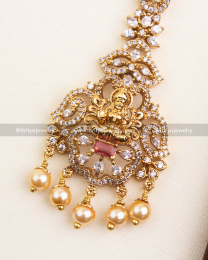 Detailed view of temple-style red maang tikka with goddess motif, CZ stones, and pearl danglers.