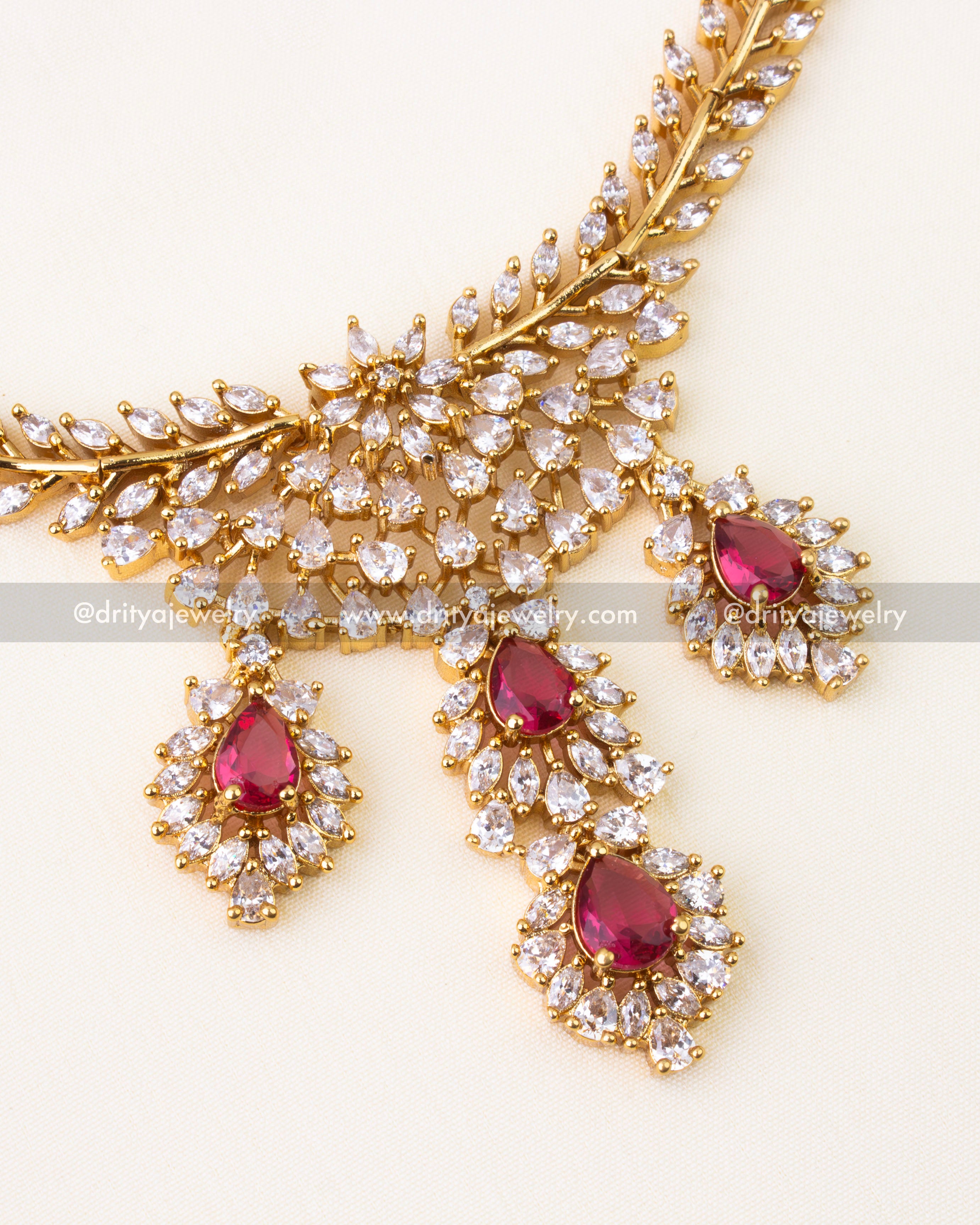 Ruby red teardrop stones surrounded by CZ diamonds in gold setting.