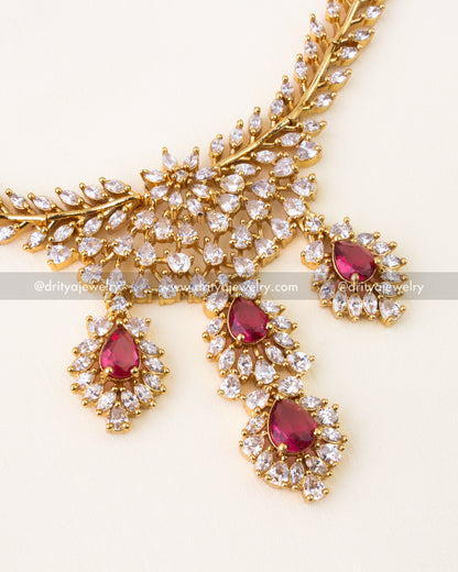 Ruby red teardrop stones surrounded by CZ diamonds in gold setting.
