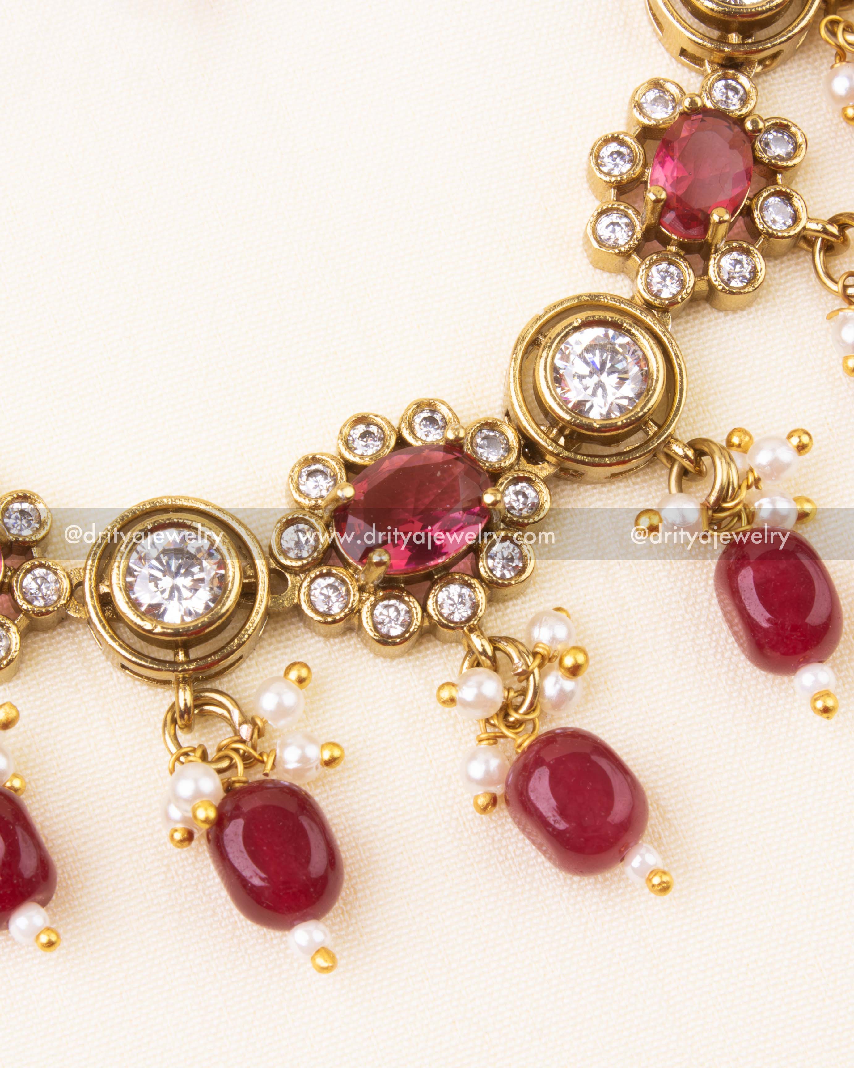 Detailed view of ruby red beads and CZ stones in a Victorian finish necklace.