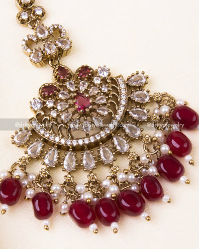 Detailed Victorian-style maang tikka with red beads and pearl hangings.