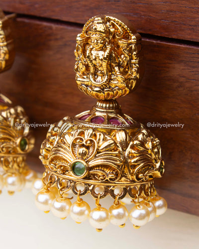 Detailed close-up of small temple Jhumka earrings with goddess motif and fine nakshi work.