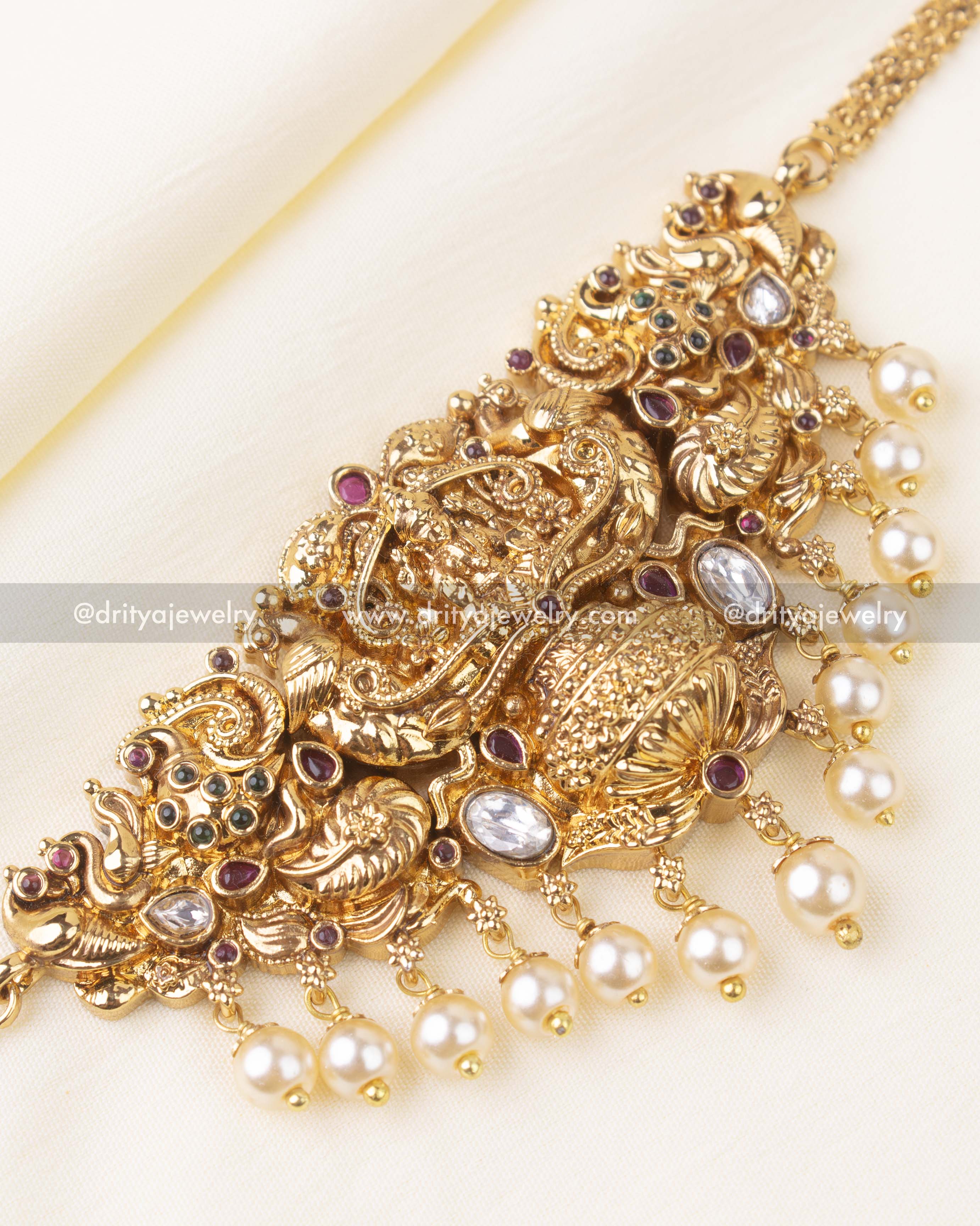 Detailed view of Lakshmi, peacock engravings, and pearl embellishments