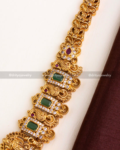 Intricate temple-style chain with green rectangular stones, ruby florals, and American Diamonds in antique finish.