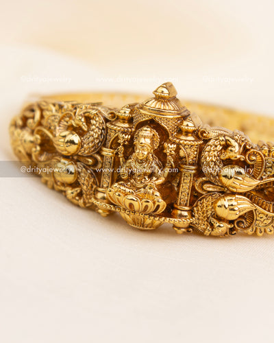Detailed view of Lakshmi Devi surrounded by peacocks and pillar carvings on temple-style kada.