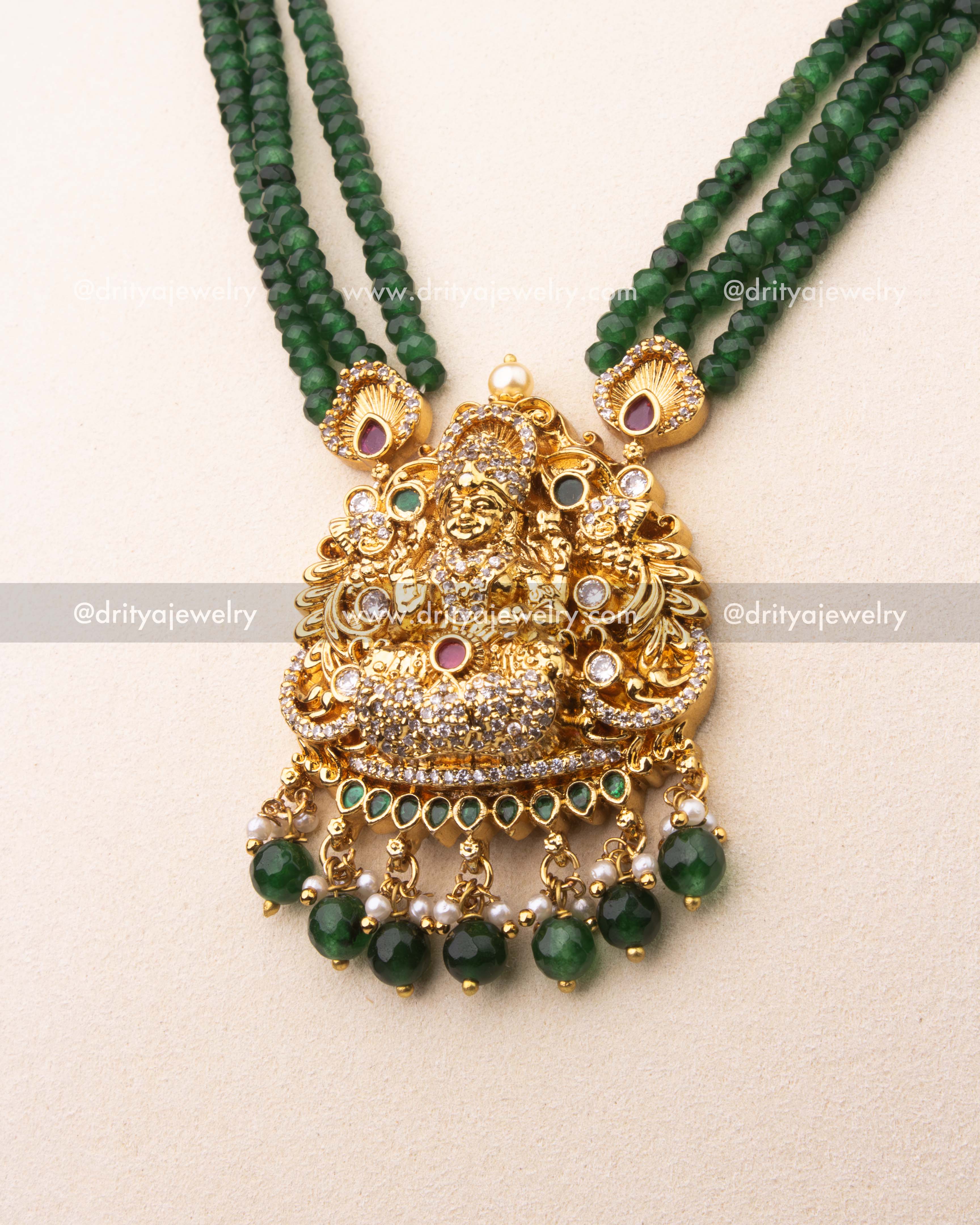 Intricately designed Lakshmi pendant with CZ stones, ruby detailing, and green bead hangings.