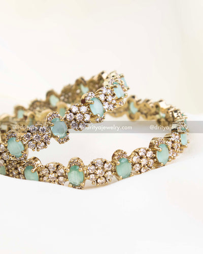 Detailed mint green Victorian bangles with oval stones surrounded by white crystals.