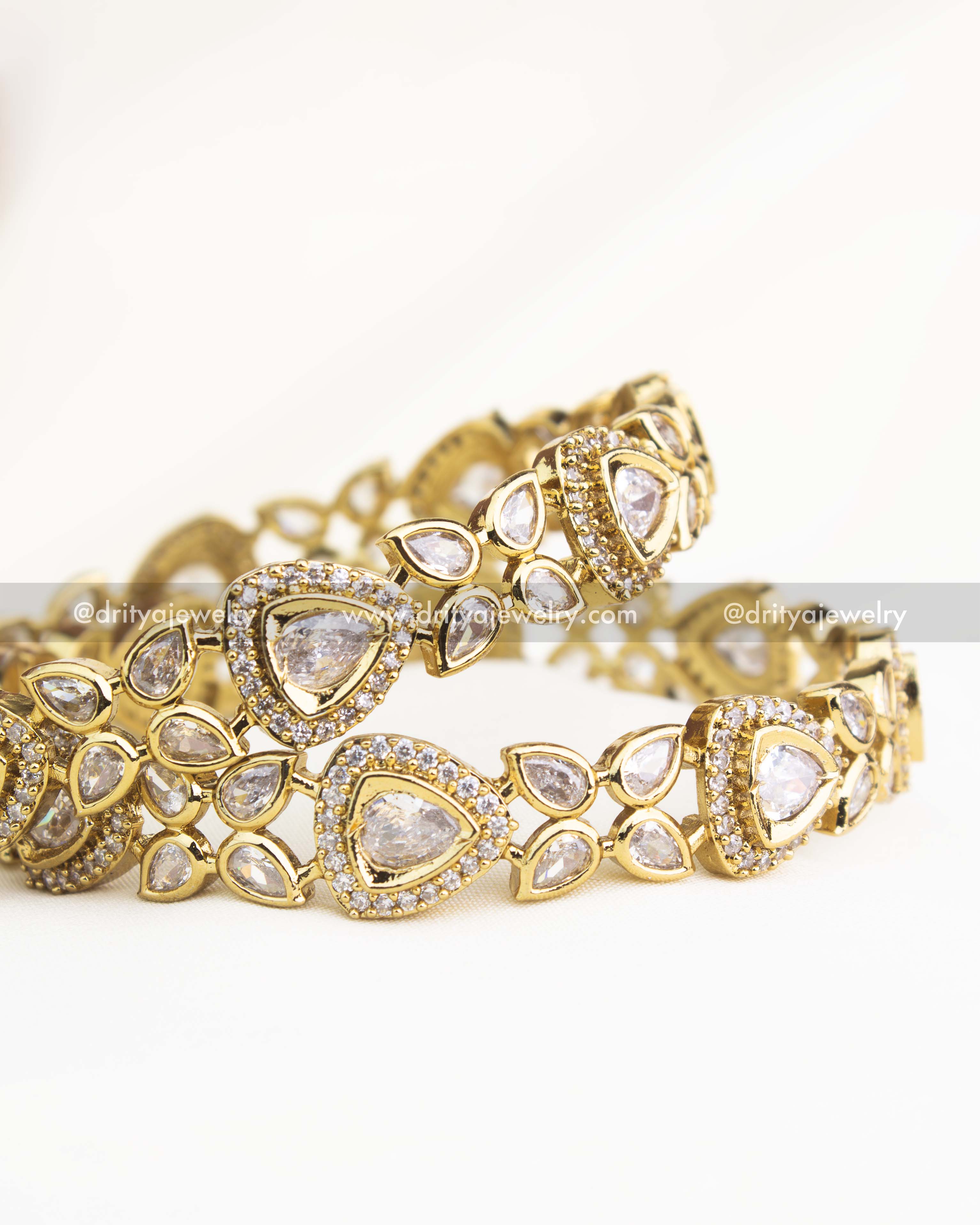 Premium Victorian diamond-white AD stone bangles with teardrop and triangular motifs in gold polish by Dritya Jewelry.