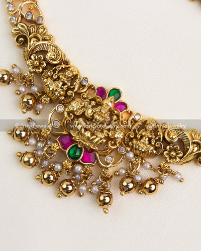 Close-up showing intricate temple pendant with ruby-green kemp stones, pearls, and gold bead detailing.