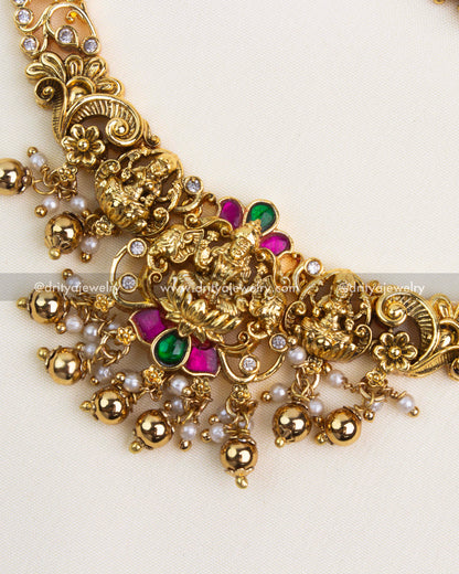 Close-up showing intricate temple pendant with ruby-green kemp stones, pearls, and gold bead detailing.