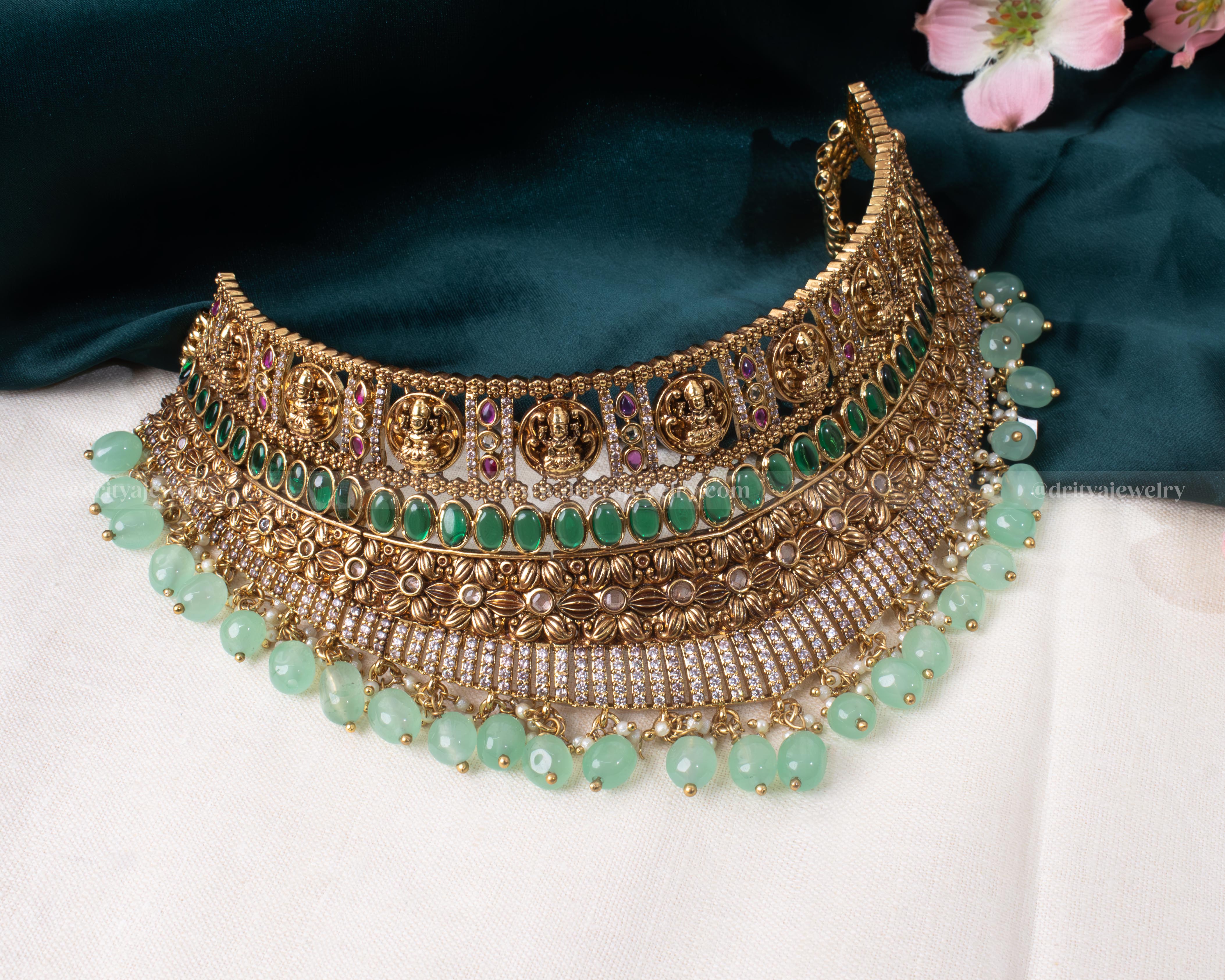 Close-up view showing detailed craftsmanship of Goddess Lakshmi motif on gold choker with green beads by Dritya Jewelry.