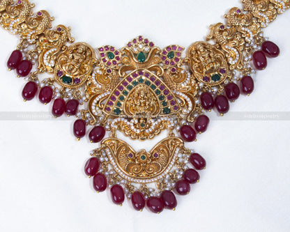 Detailed close-up of the Lakshmi Devi motif on a gold bridal necklace, embellished with gemstones and pearls by Dritya Jewelry.