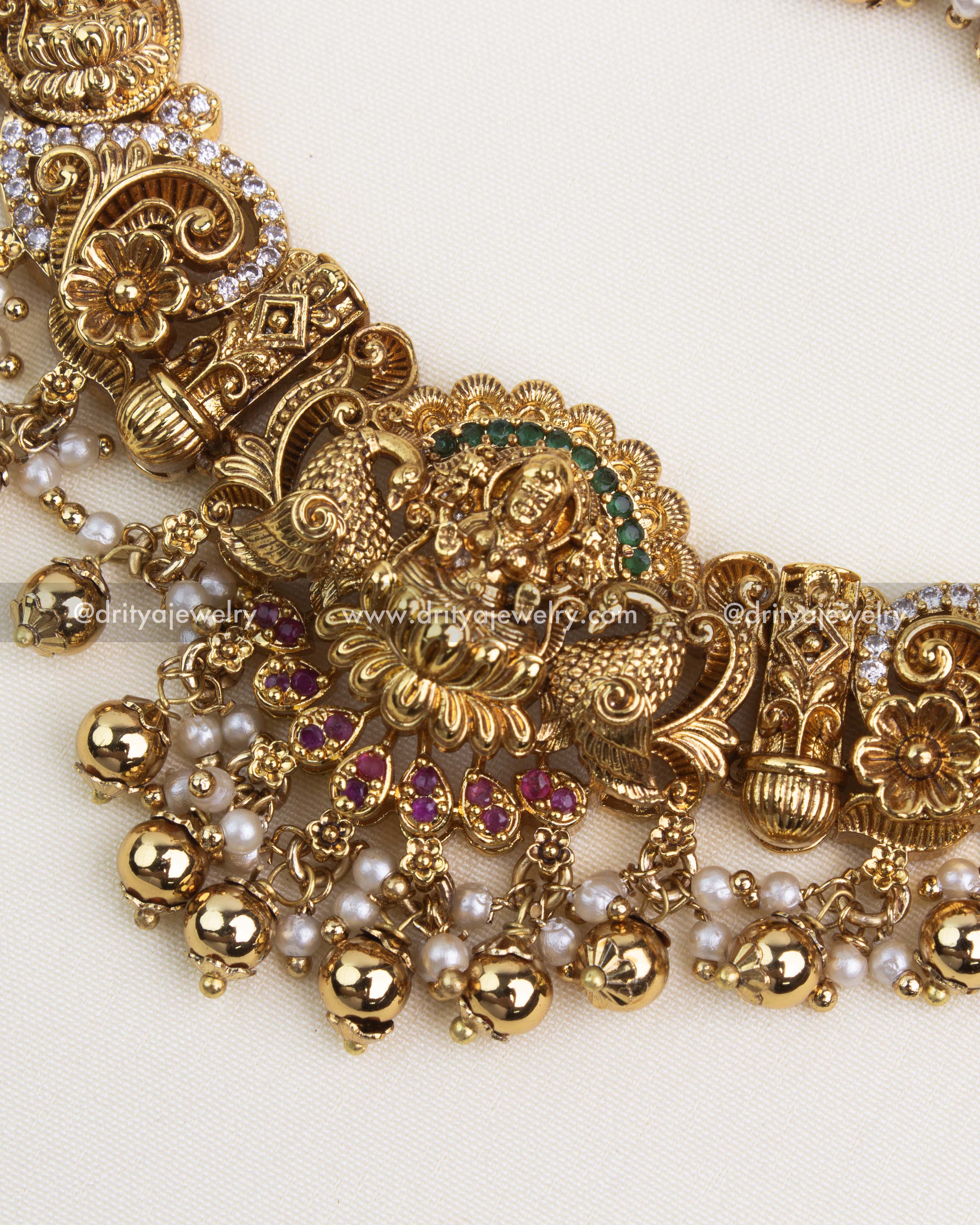 Close-up of gold-plated Nakshi pendant with ruby and white stones and gold ball detailing.