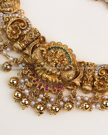 Close-up of gold-plated Nakshi pendant with ruby and white stones and gold ball detailing.