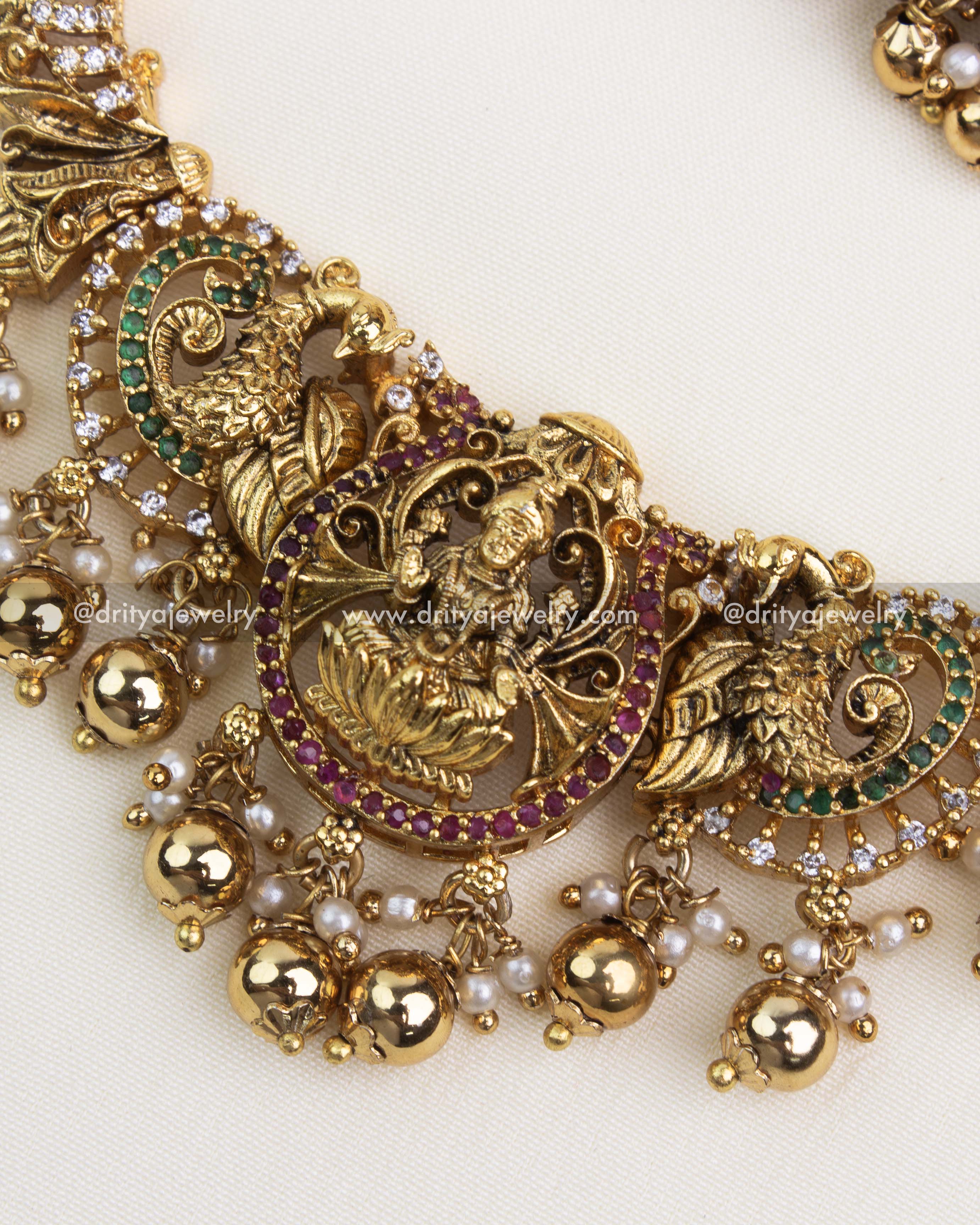 Detailed temple pendant with ruby and emerald accents, goddess Lakshmi engraving, and gold ball detailing.