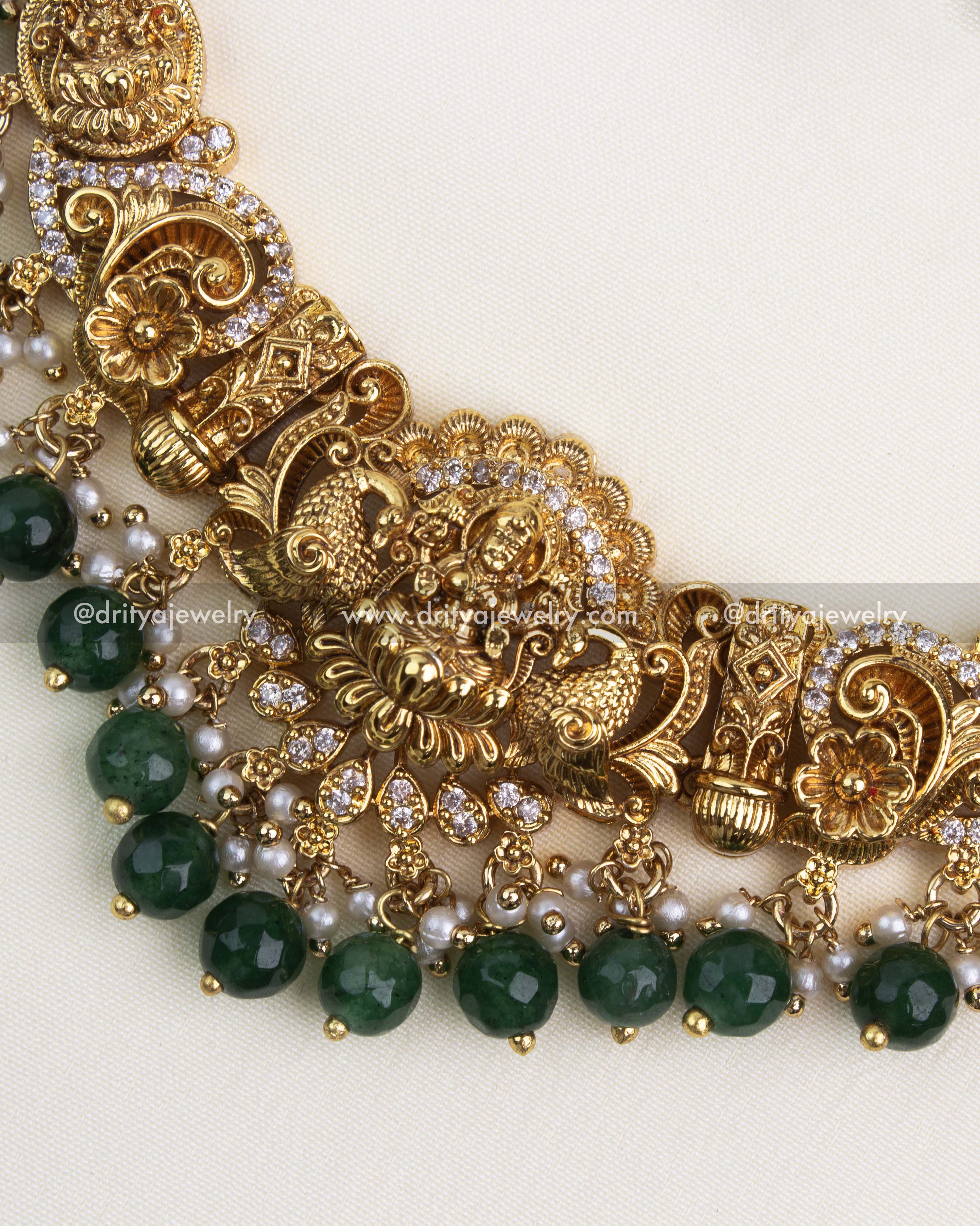 Detailed close-up of antique gold Nakshi pendant with white stones and green bead edging.