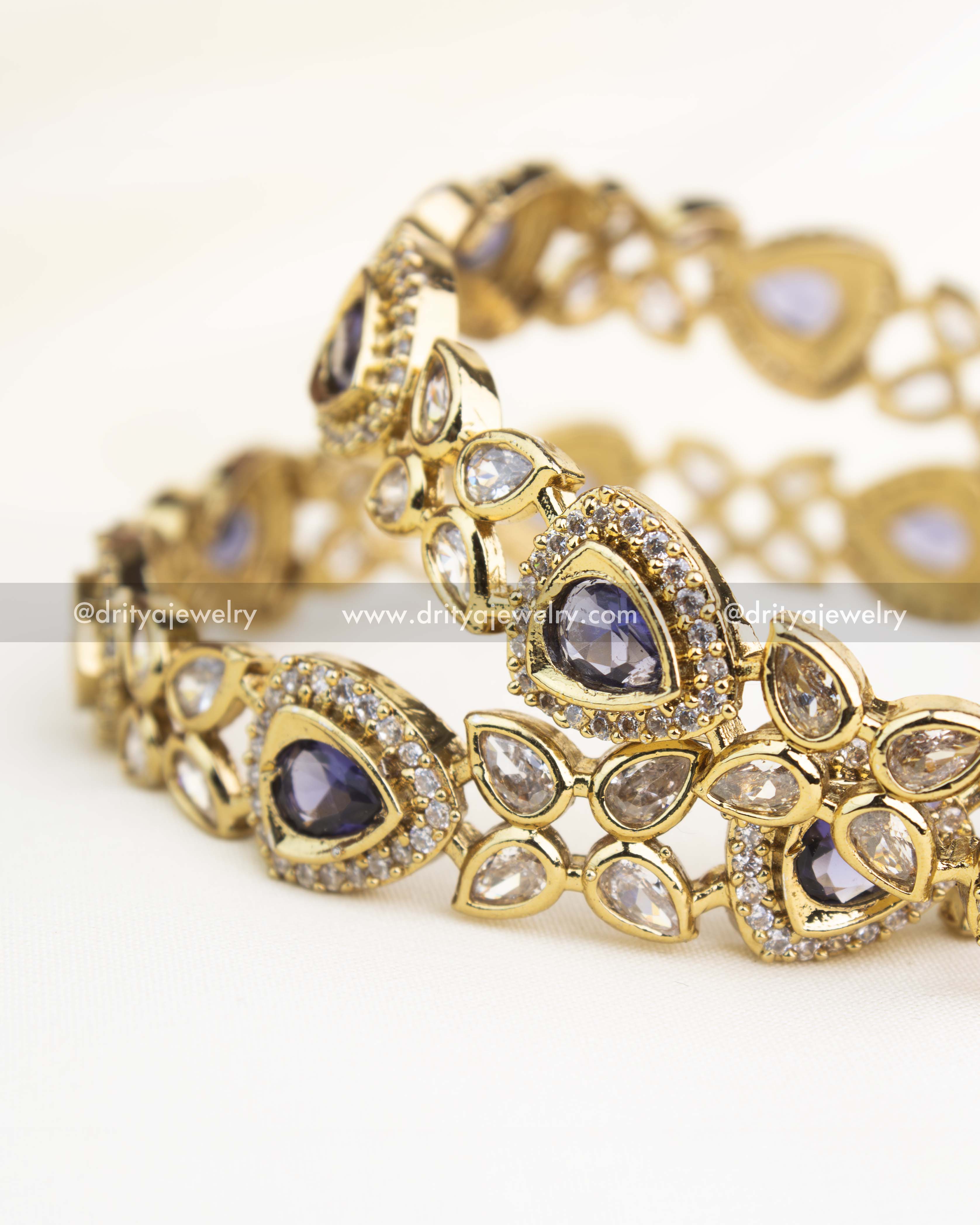 Close-up showing intricate AD work and teardrop purple stones on gold-finished Victorian bangles.